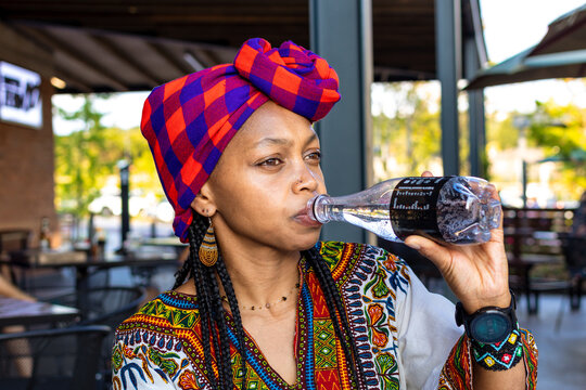 Beautiful african lady wearing a doek or headcover drinking sparkling water