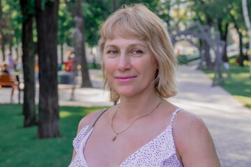 Fototapeta premium Portrait of a middle-aged blonde woman pretty smiling on the background of summer nature