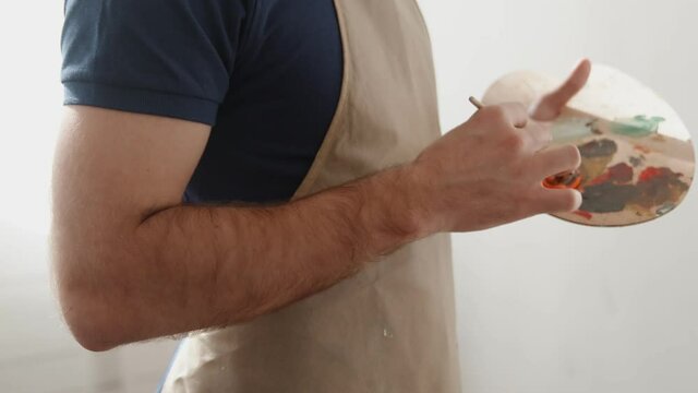 Side view of man with apron Draws paints on canvas drawing picture in his art studio