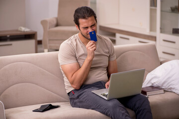 Young man ordering goods by credit card at home