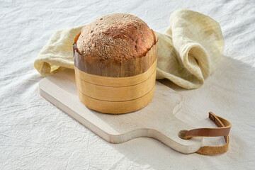 Dinkelbrot in German that means spelt. Loaf of wholemeal dinkel rye bread. Dinkel or Spelt is healthy alternative to wheat. Off white textile tablecloth and linen towel. Wheat ear decorations.