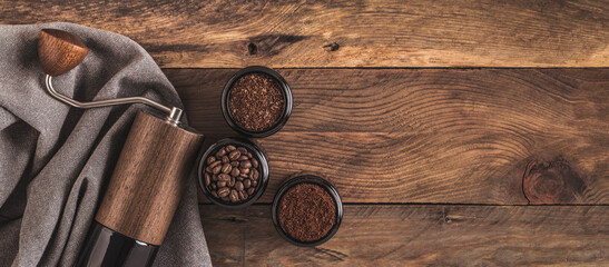 Manual Coffee grinder and jars of fresh ground coffee from roasted beans on wooden rustic table....