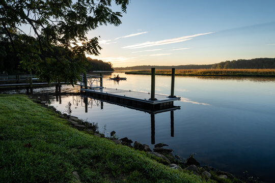 Lone Small Fishing Boat Near Floating Dock on a Calm River in Autumn at Sunrise
