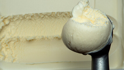 Ice cream Vanilla scooped out from container with a spoon.