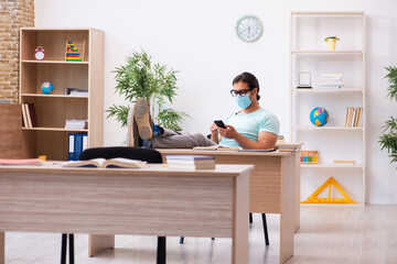 Young male student sitting in the classroom wearing mask