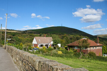 Mossley, England - A charming, typical rural English house, against the rolling hills of Mossley, under a blue sky with clouds.  Image has copy space.