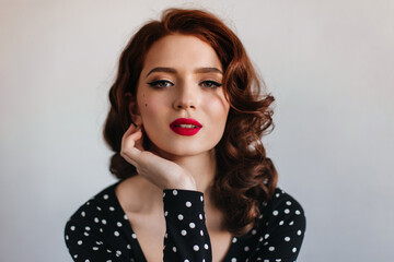 Charming female model looking at camera. Sensual red-haired girl posing on grey background.
