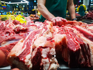 large cuts of raw beef and lamb meat sold in a butcher shop in a large food market