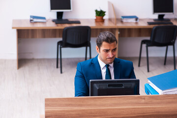 Young male employee unhappy with excessive work in the office