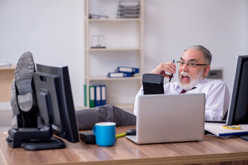 Fototapeta premium Old male boss sitting at desktop in the office