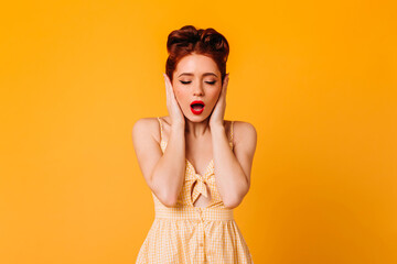 Sensual ginger girl covering ears with hands. Studio shot of emotional stylish woman in dress...