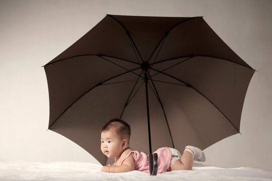 A Baby Under A Big Black Umbrella