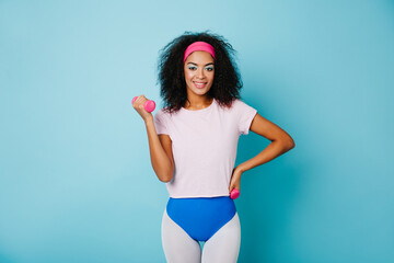 Studio shot of wonderful sporty girl isolated on blue background. Pretty african woman training...
