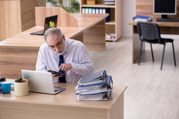 Fototapeta premium Old male employee working in the office