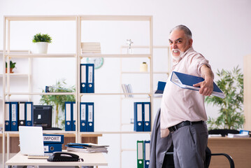 Fototapeta premium Old male employee doing physical exercises at workplace