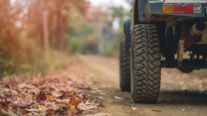 Part of an off-road vehicle on a rugged road in the forest . Travel concept with sunset and...