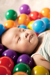 Fototapeta na wymiar A baby boy surrounding by color balls