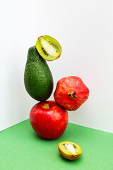 A stack of fruit, apple, avocado, pomegranate and kiwi. 