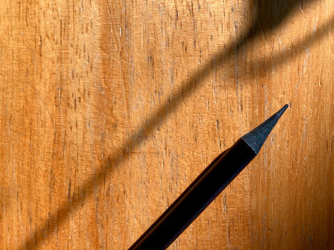 black pencil on brown wooden table with shaded of shadow