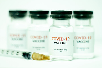 vials of covid-19 vaccine in a row with syringe