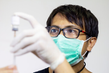 doctor trasferring the vaccine to the syringe