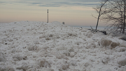 Frozen shoreline of Lake Michigan after a winter storm. Snow drifts formed at the water's edge and ice balls formed  from the rolling waves. Taken at Gillson Beach in Wilmette, Illinois.