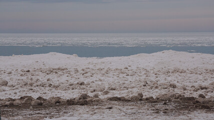 Frozen shoreline of Lake Michigan after a winter storm. Snow drifts formed at the water's edge and ice balls formed  from the rolling waves. Taken at Gillson Beach in Wilmette, Illinois.