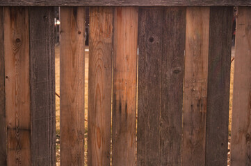 A weathered wooden fence has faded and taken on different shades of brown. 