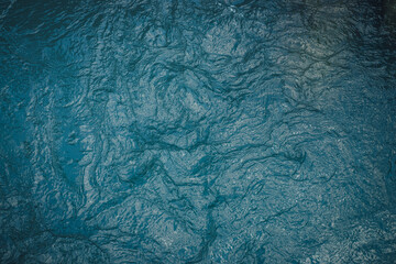 Texture of dark blue calm water of lake. Meditative ripples on water surface. Nature minimal background of deep green lake. Natural backdrop of clear dark turquoise water. Full frame of lake fragment.