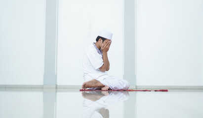 A portrait of an asian muslim man pray at mosque, the pray name is sholat, regards end of sholat