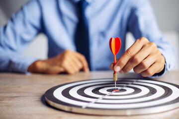 Businessman holding a darts aiming at the target center business goal concept - business targeting,...