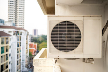 Closeup of air conditioner compressor outside building.