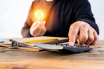 Human hand holds a light bulb and presses a calculator to calculate the company energy