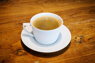 Hot coffee in a white cup on a wooden table