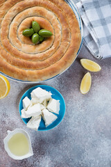 Top view of spanakopita or greek spinach and feta cheese pie, vertical shot on a beige stone surface with copyspace