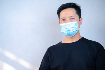 Portrait of tired young man in blue medical mask on face for personal protection