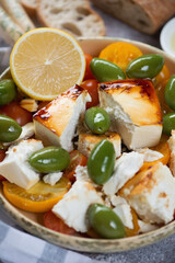 Chunks of feta cheese baked with tomatoes and giant green olives, vertical shot, closeup