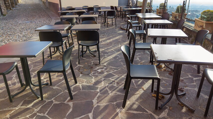 Bergamo, Italy. Empty bar tables due to the Covid-19 or Coronavirus pandemic. Light lockdown time. Bars and restaurants closed due to the absence of tourists. Desolation and sadness for empty city