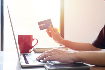 Woman is holding credit card and using laptop computer