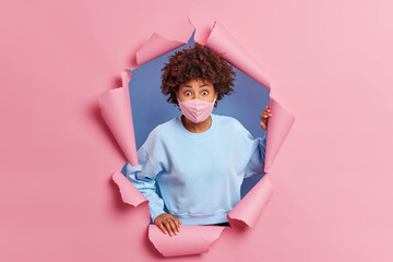 Covid 19 pandemic and health care concept. Wondered curly haired Afro American woman in face mask...
