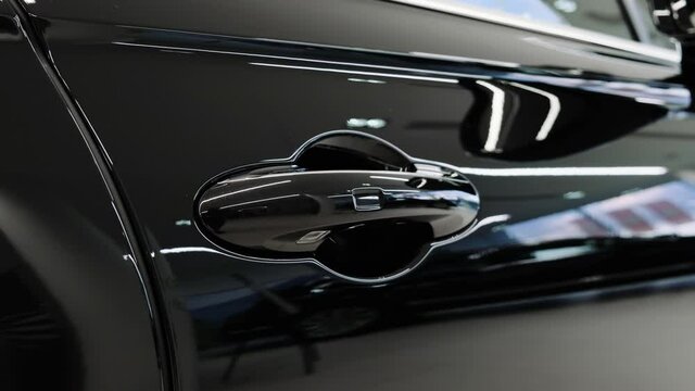 Door handle of a new black luxury car in a car dealer showroom