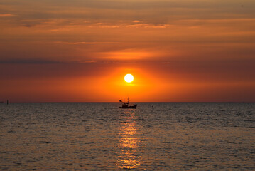 A beautiful sunset in the evening A fisherman's boat passed at Bang Saen Beach, Thailand.