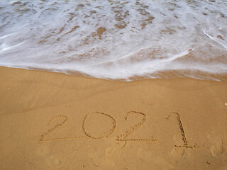 Message Year 2021 written on beach sand for background