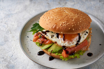 Tasty homemade sandwich with salmon , fried egg ,herbs and avocado