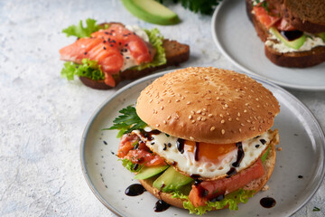 Tasty homemade sandwich with salmon , fried egg ,herbs and avocado