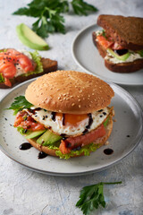 Tasty homemade sandwich with salmon , fried egg ,herbs and avocado