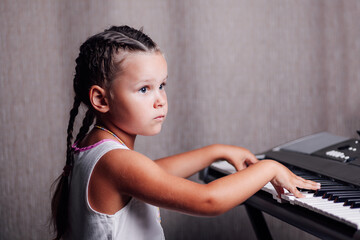 close-up portrait of a serious, diligent girl in a white summer dress and two pigtails playing a...