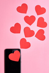 Paper hearts flying out of a smartphone, Valentine's day, love and technology concept.