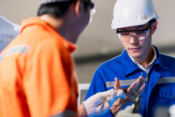 Male Asian engineer professional  having a discussion standing by the machine in the factory ,two asian coworker brainstorm explaining and solves the process curcuit mother board of the machine
