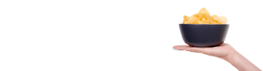 Hand with golden potato chip in dark bowl, isolated on white background.